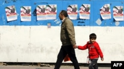 یک مرد در حال عبور از مقابل پوسترهای تبلیغاتی یکی از نامزدان انتخابات پارلمانی ایران، در تهران.