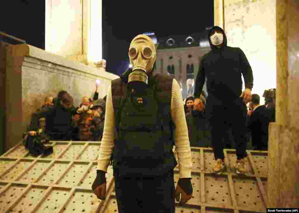 A protester wears a gas mask at the entrance to the parliament building, on Tbilisi's Shota Rustaveli Avenue, after a steel barrier designed to stop protesters was toppled. 