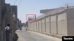 در عکس تسنیم، برجک کلانتری مشخص شده و یک نیروی لباس‌شخصی (چپ) اسلحه‌اش را به آن سمت نشانه رفته است