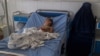 A burqa-clad Afghan woman sits next to a child receiving treatment at a hospital after he was injured in a bomb blast in Kunduz on April 21.
