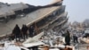 People look at rubble and damage following an earthquake in Hatay, Turkey
