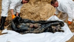 Criminaliștii inspectează un cadavru găsit în groapa comună de lângă Izium, 16 septembrie 2022.