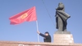 Un bărbat flutură steagul kirghiz lângă statuia liderului bolșevic Vladimir Lenin din centrul orașului Oș. Autoritățile locale au demontat statuia în luna iunie.