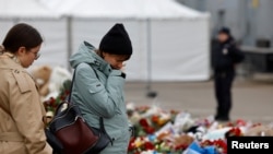 Women pay their respects to the victims of the Crocus City Hall shooting attack at an impromptu memorial near the venue.