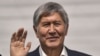 Ex-President Almazbek Atambaev waves as he stands inside a defendants' cage during a court hearing in Bishkek on November 27.