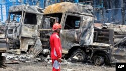 A rescue worker stands in front of burned vehicles after a massive explosion and fire rocked the Shahid Rajaei port near the southern port city of Bandar Abbas, Iran, on April 26