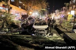 Силы безопасности Израиля проходят мимо сгоревших автомобилей в Холоне недалеко от Тель-Авива 11 мая 2021 года после того, как члены ХАМАС выпустили в направлении Израиля несколько ракет.