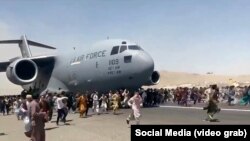 Люди на взлетном поле в аэропорту Кабула пытаются не дать взлететь американскому военно-транспортному самолету. 18 августа 2021 г.