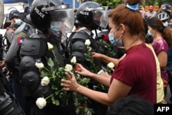 Протестующие вставляют цветы в щиты полицейских во время протестов в Янгоне, 6 февраля.