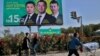 A Kyrgyz boy in the city of Kant walks past a poster of candidates in upcoming parliamentary elections, which are due to take place on October 4. 